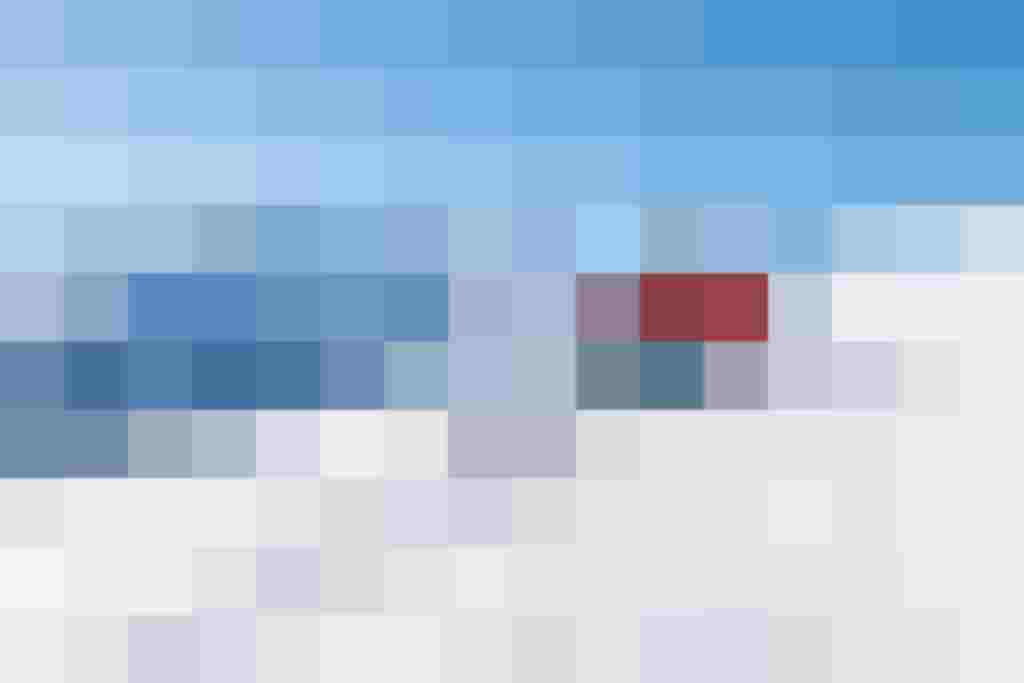 Skifahrer auf einer Piste mit schneebedeckten Bergen im Hintergrund, klare Himmel.