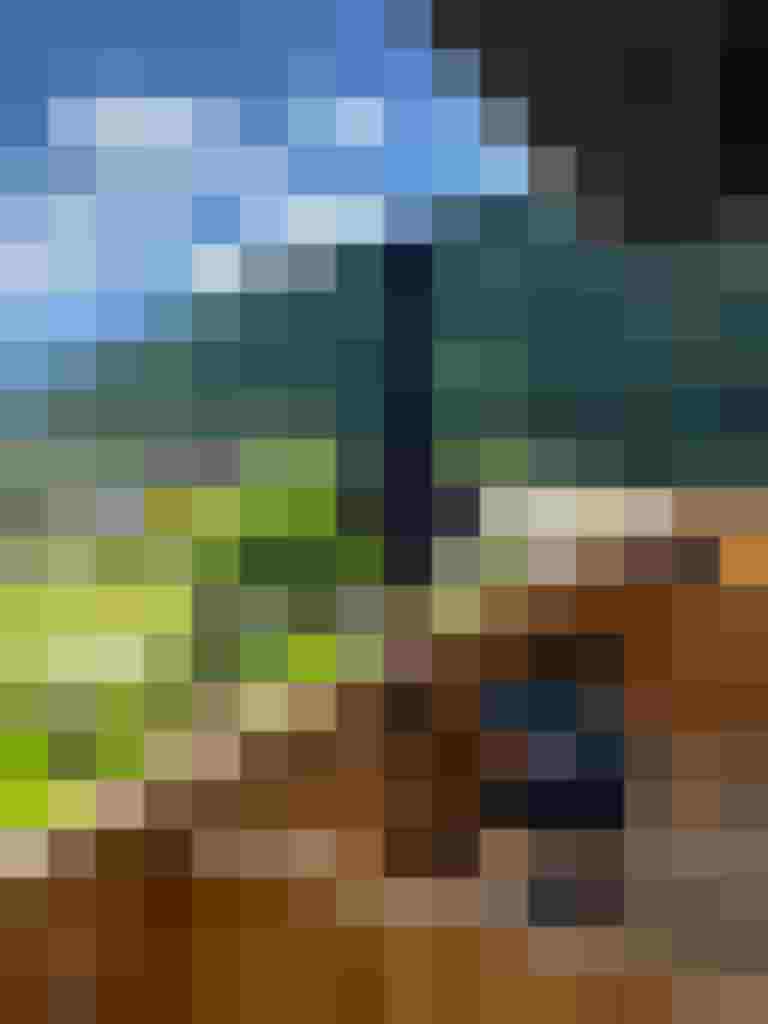 Holzbalkon mit Sitzbereich und Blick auf grünen Hang und Dorfwiese