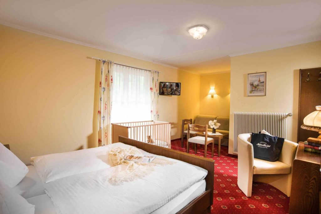 Gemütliches Zimmer im Hotel Steindlwirt mit Doppelbett und Sitzecke für Familien.