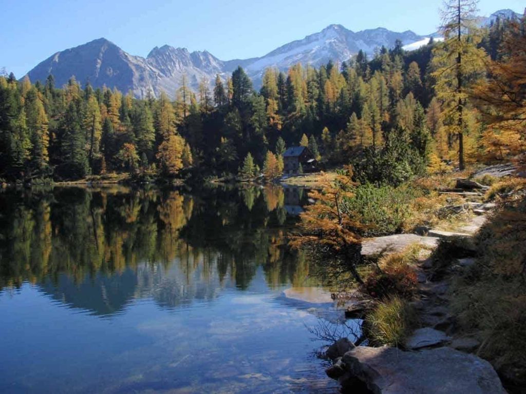 Herbstlicher Bergsee mit Wald und reflektierenden Bergen, ideal für Familienaktivitäten.