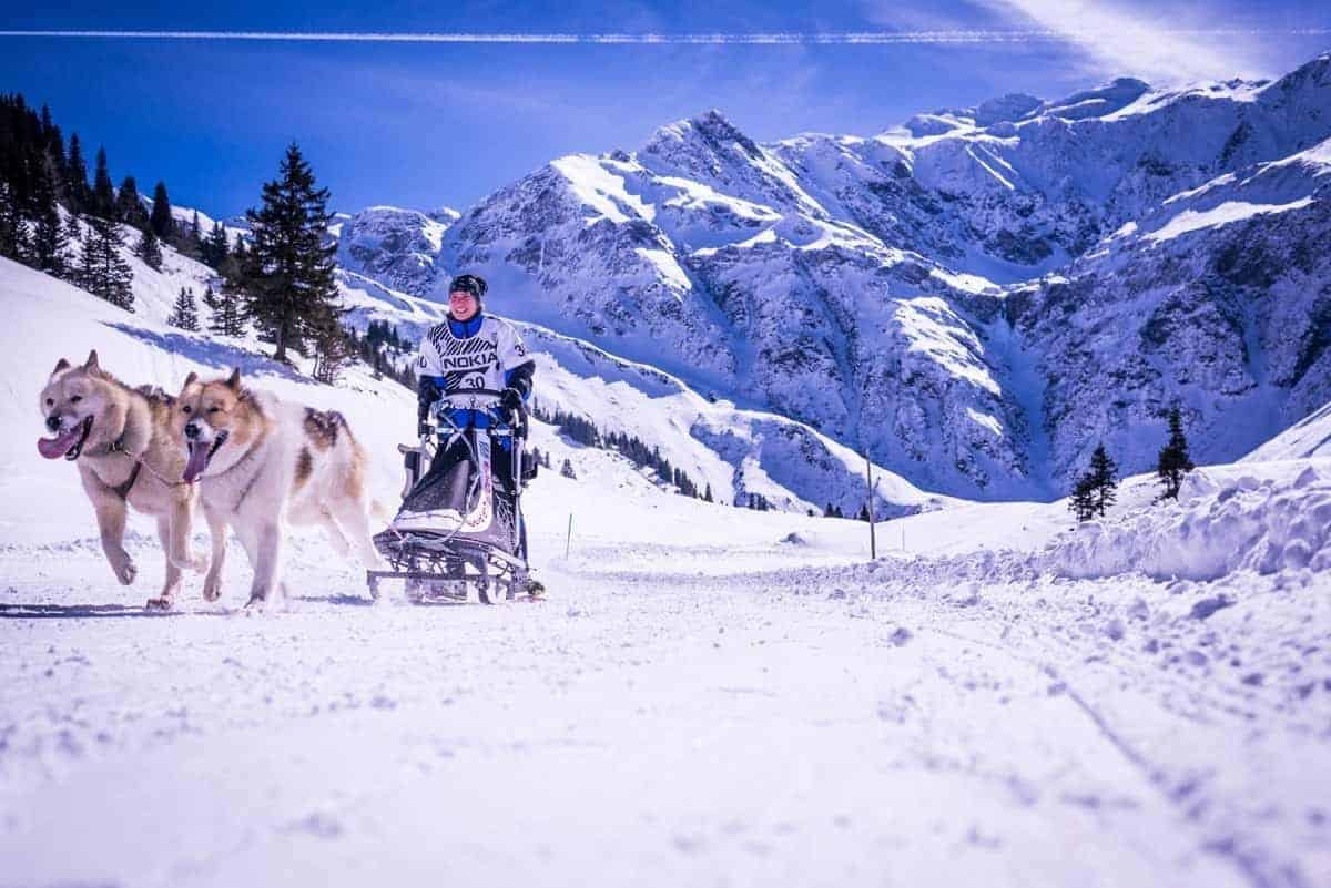 Hundeschlittenfahrt durch verschneite Berge im Gasteinertal, ideal für Winterurlaub.