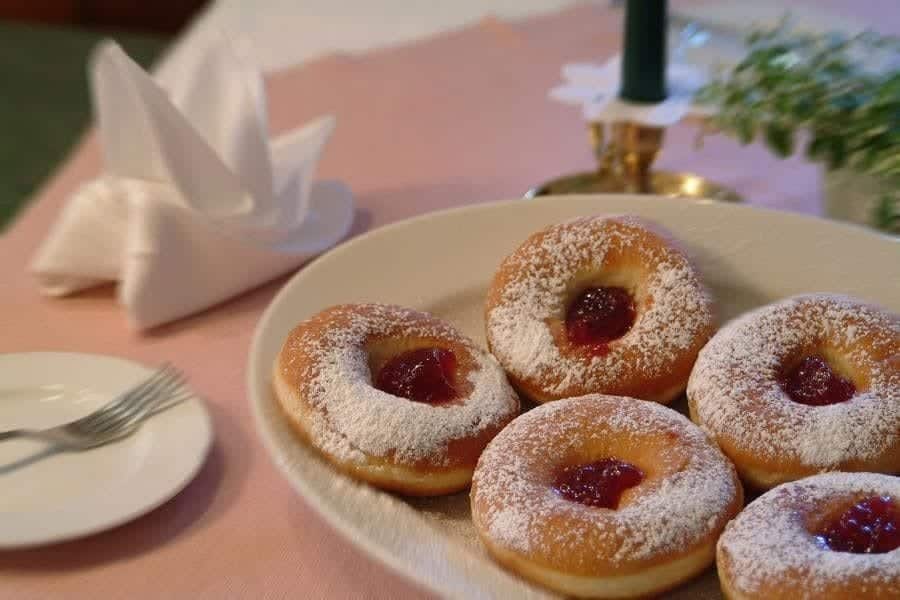 Hausgemachte, mit Puderzucker bestreute Krapfen auf einem Teller im Hotel Steindlwirt.