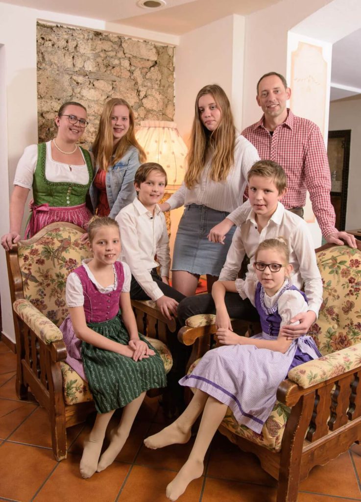 Familienbild mit fröhlichen Kindern und Erwachsenen in traditioneller Tracht im Hotel Steindlwirt.