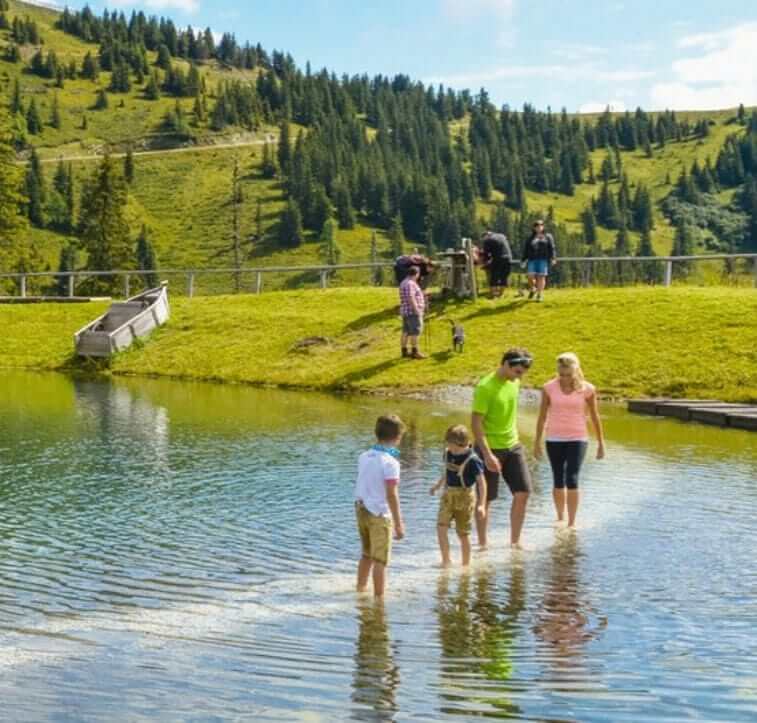 Family in the water, surrounded by mountains and nature, ideal for a family vacation.