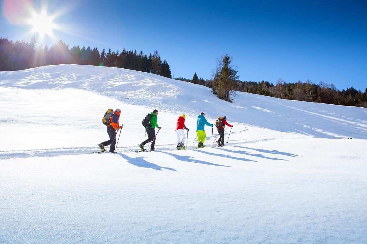 Skiwanderer auf unberührtem Schnee, umgeben von strahlender Winterlandschaft.