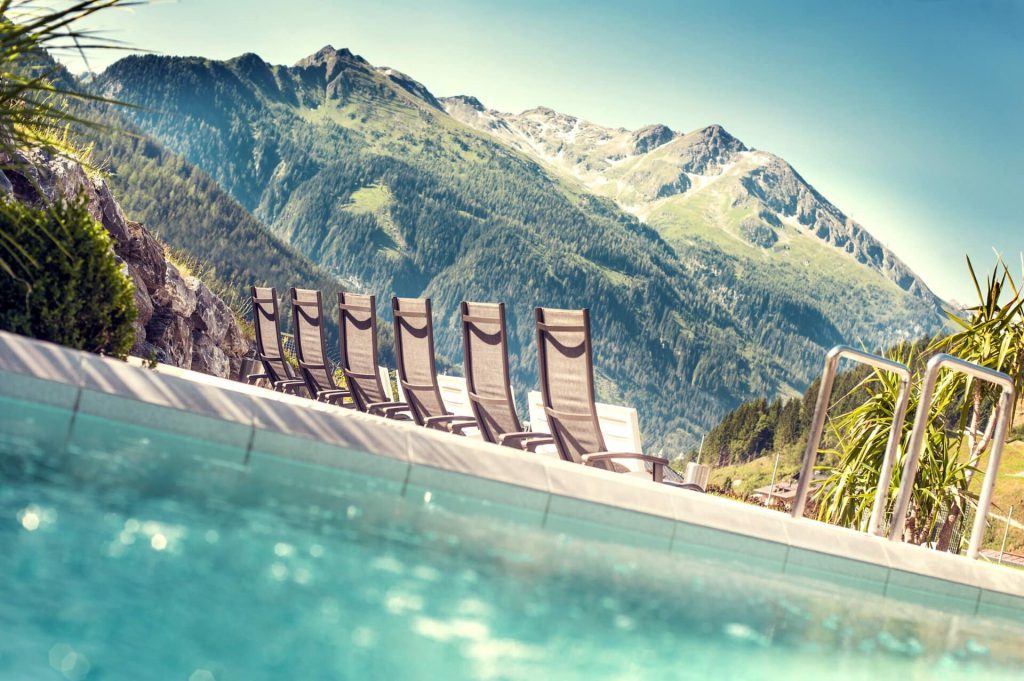 Relaxing loungers by the outdoor pool with a view of the mountains in Salzburger Land.