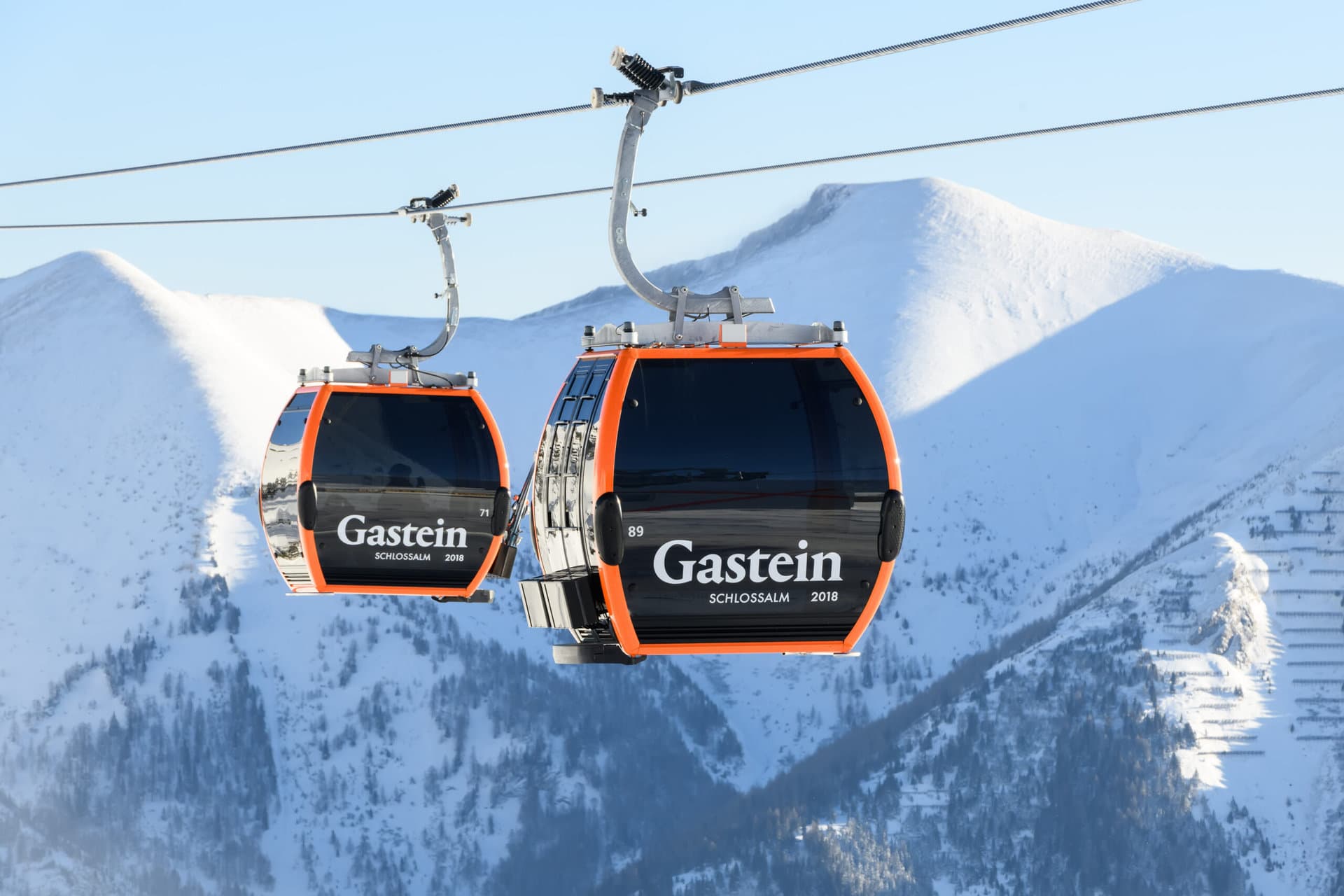 Zwei Seilbahnkabinen in der Gastein-Region vor schneebedeckten Bergen. Ideal für Skiurlaub.