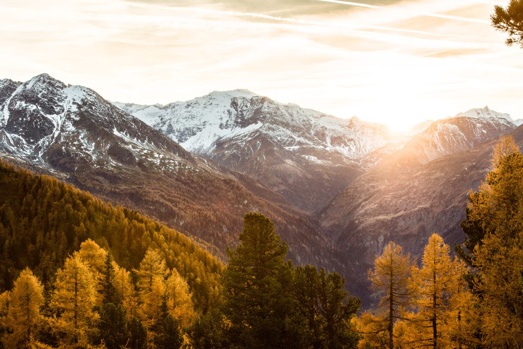Sonnenaufgang über verschneiten Bergen und herbstlichen Wäldern im Gasteinertal