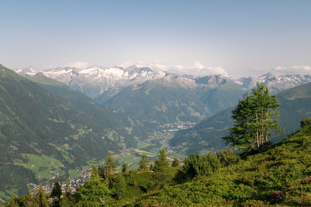 Blick ins Gasteinertal mit grünen Bergen, verschneiten Gipfeln und Talort Dorfgastein