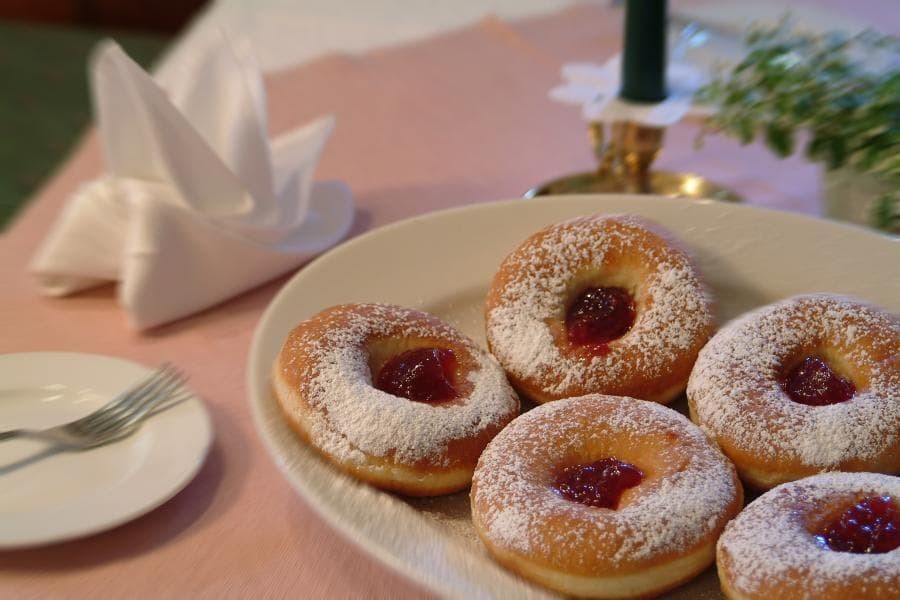 Fünf Krapfen mit Puderzucker und Marmelade auf Teller