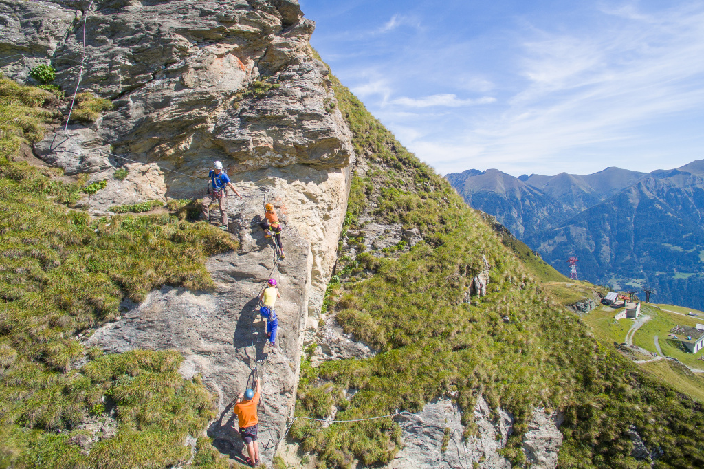 Gruppe am Klettersteig an einer Felswand mit Bergpanorama im Gasteinertal