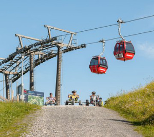 Mountaincarts an der Bergstation Dorfgastein, daneben rote Gondelbahn vor blauem Himmel
