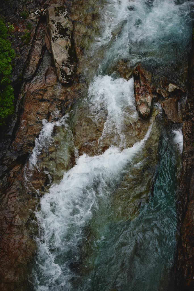 Blick von oben auf schnell fließendes Wasser zwischen dunklen Felsen der Gasteiner Ache